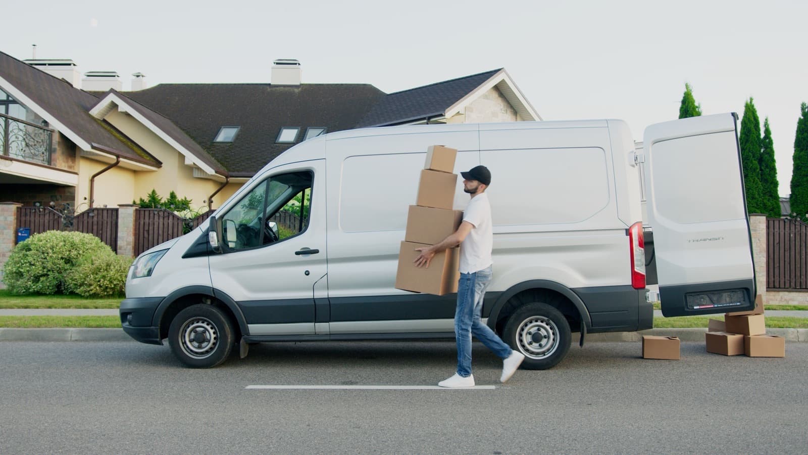 Déménageur chargeant des cartons dans une camionnette garée devant une maison