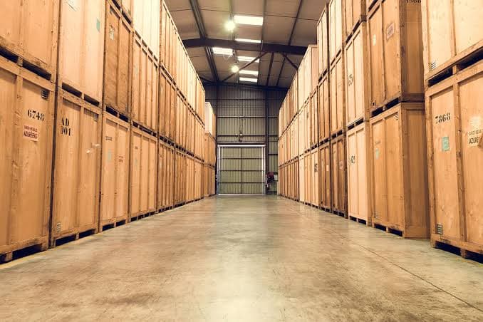Allée d'un dépôt de déménageur, caisses en bois numérotées empilées de chaque côté