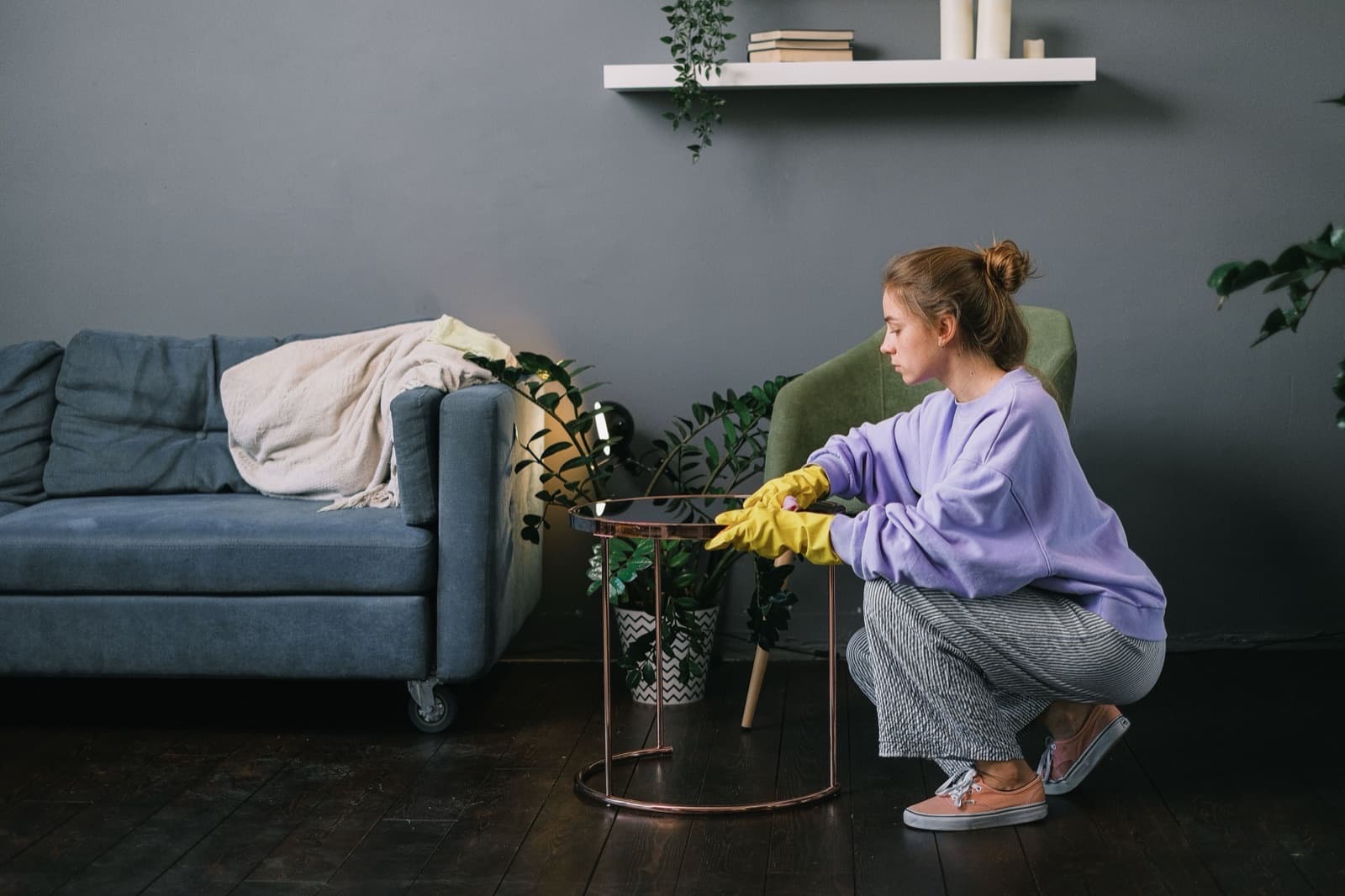 Nettoyage d'un salon genevois : dépoussiérage d'une table basse avec des gants de ménage