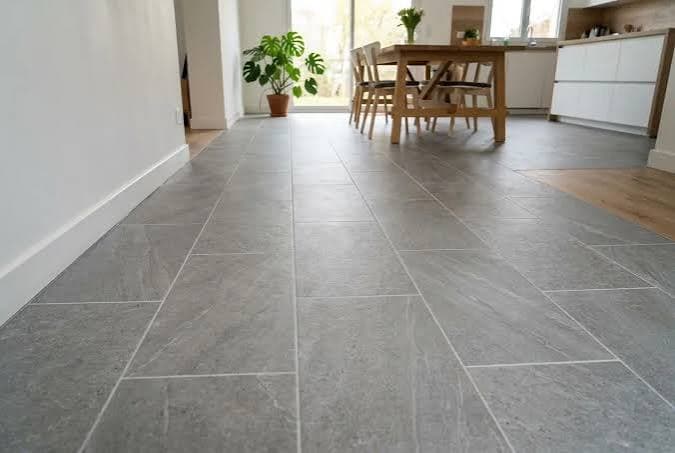 Grands carreaux gris rectangulaires posés au sol d'un séjour ouvert sur la cuisine