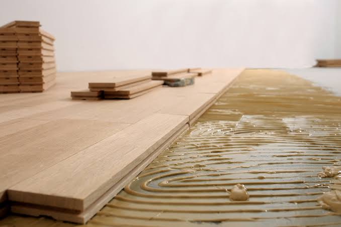 Lames de parquet posées sur une colle étalée en sillons, pose collée en cours